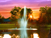 Atriarch Fountain by Scott Aerator glowing over a pond at sunset