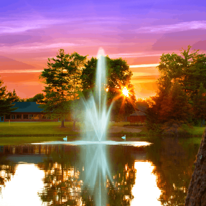 Atriarch Fountain by Scott Aerator glowing over a pond at sunset