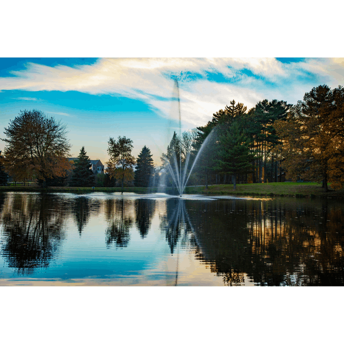 Atriarch Fountain by Scott Aerator spraying against a vivid sunset over a reflective pond