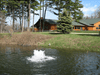 Boilermaker Pond Aerator by Scott Aerator creating a low-profile white boil near a lakeside cabin