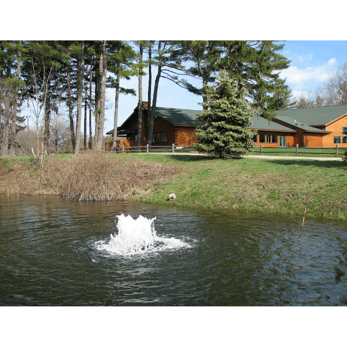 Boilermaker Pond Aerator by Scott Aerator creating a low-profile white boil near a lakeside cabin