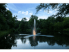 Clover Pond Fountain by Scott Aerator glowing at dusk on a wooded pond