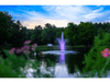 Distant view of the Scott Aerator Amherst Pond Fountain glowing with purple lighting at night