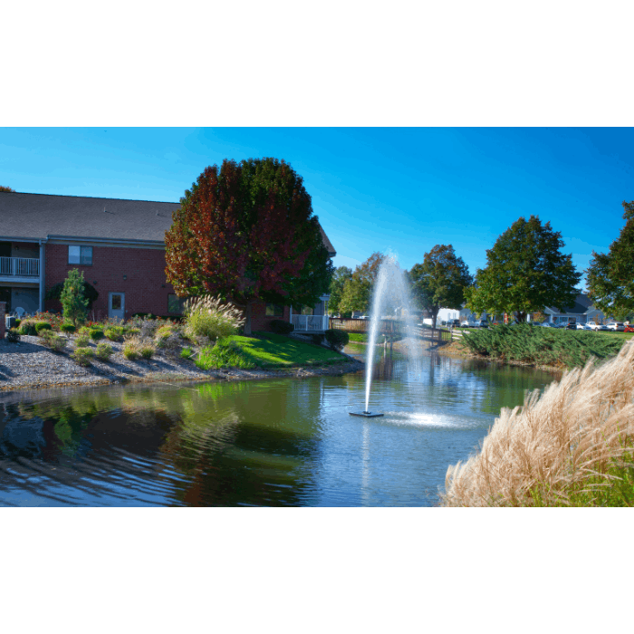 Gusher Pond Fountain by Scott Aerator operating in a landscaped pond beside an apartment building