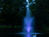 Scott Aerator Amherst Pond Fountain illuminated at night with purple LED lights in a landscaped pond
