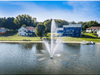 Scott Aerator Atriarch fountain spraying across a residential lake near shoreline houses