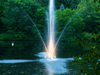 Scott Aerator Clover fountain lit at dusk with glowing center spray on a pond
