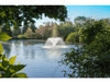 Scott Aerator DA-20 pond fountain spraying in large landscaped pond surrounded by trees