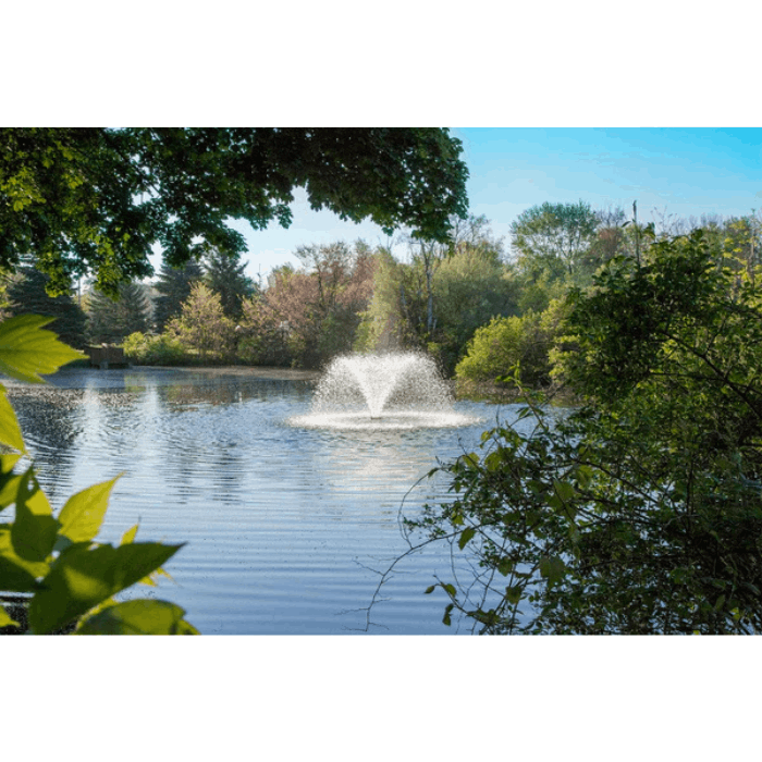 Scott Aerator DA-20 pond fountain spraying in large landscaped pond surrounded by trees
