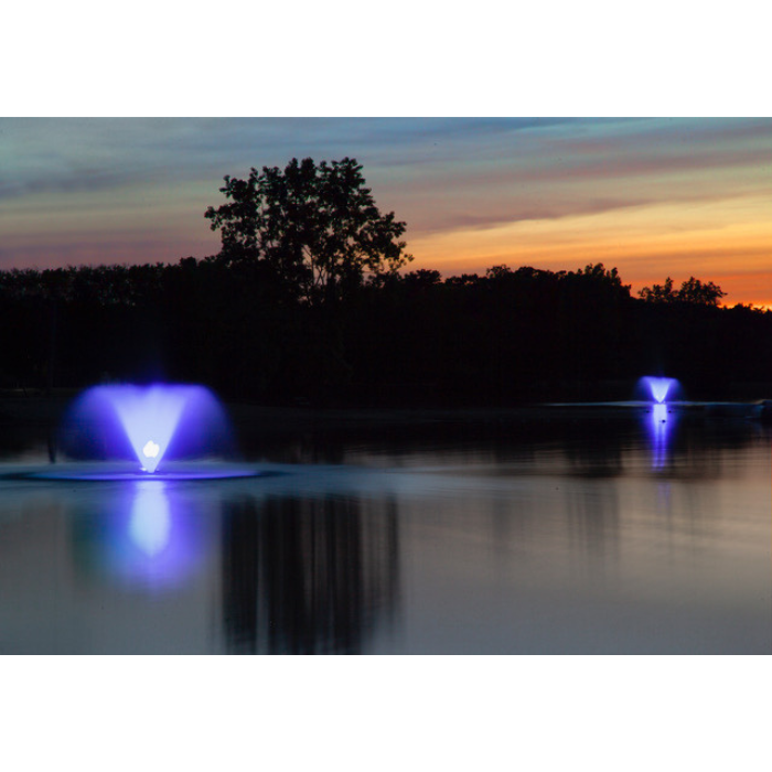 Scott Aerator North Star pond fountain illuminated blue on calm lake at dusk