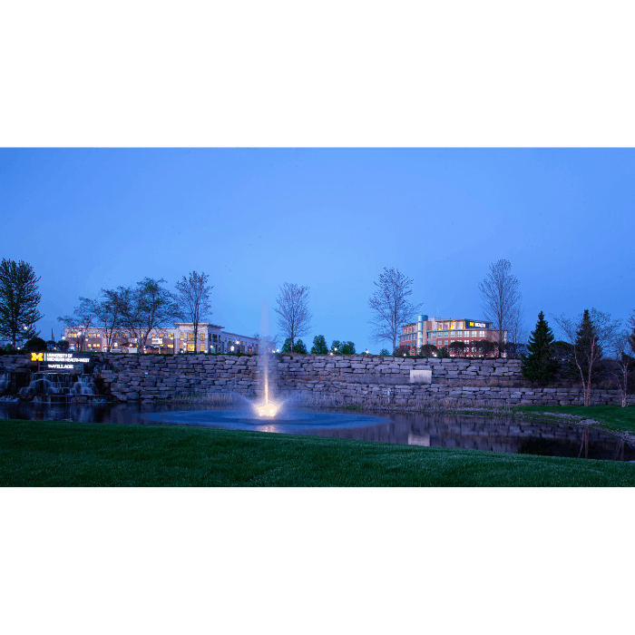 Skyward Pond Fountain by Scott Aerator illuminated in a landscaped commercial pond at dusk
