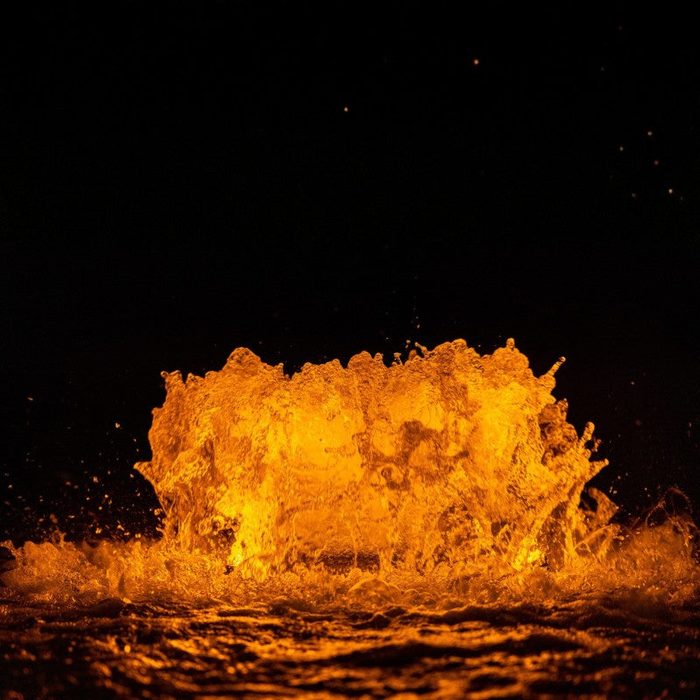 Close-up of WaterGlow RGB LED lighting creating amber illumination on fountain water splash at night