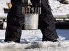 De-Icer being lowered through an ice hole by a person standing on frozen water during winter installation