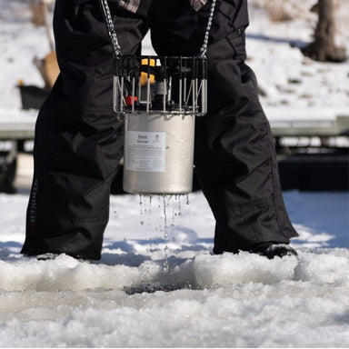 De-Icer being lowered through an ice hole by a person standing on frozen water during winter installation