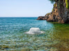 Kasco Surface Aerator creating strong water agitation in a clear coastal water setting near rocky shoreline