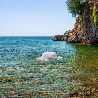 Kasco Surface Aerator creating strong water agitation in a clear coastal water setting near rocky shoreline