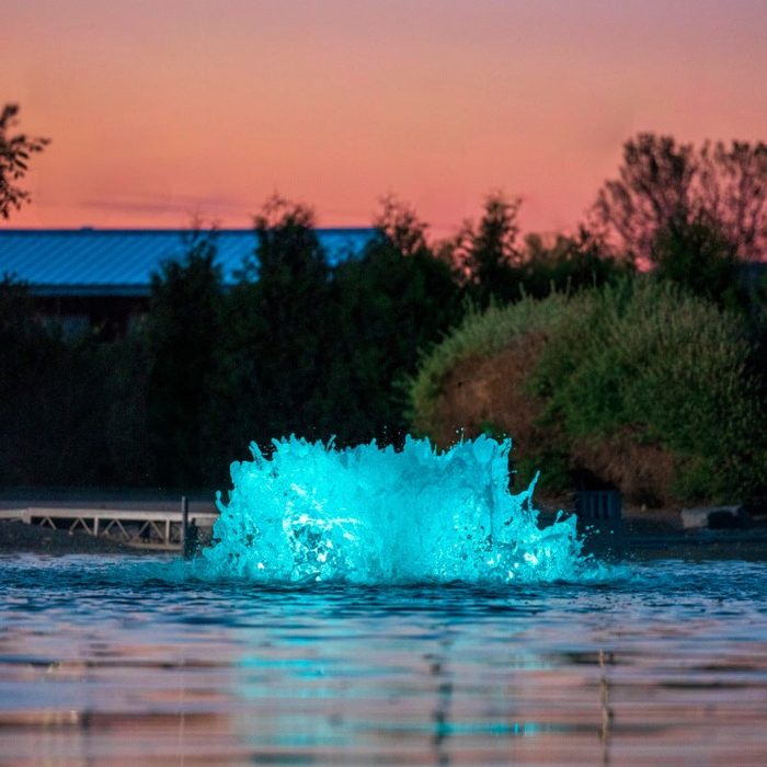 Kasco with teal LED lighting in pond at dusk