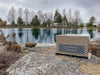 Robust-Aire System compressor cabinet installed beside pond shoreline with lake and trees in background