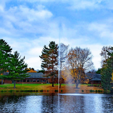 Scott Aerator Jet Stream Pond Fountain in a residential pond with a house in the background