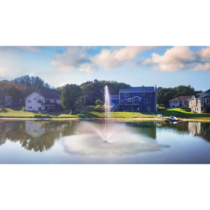 Scott Aerator Solar Skyward Fountain in a residential pond with houses in the background