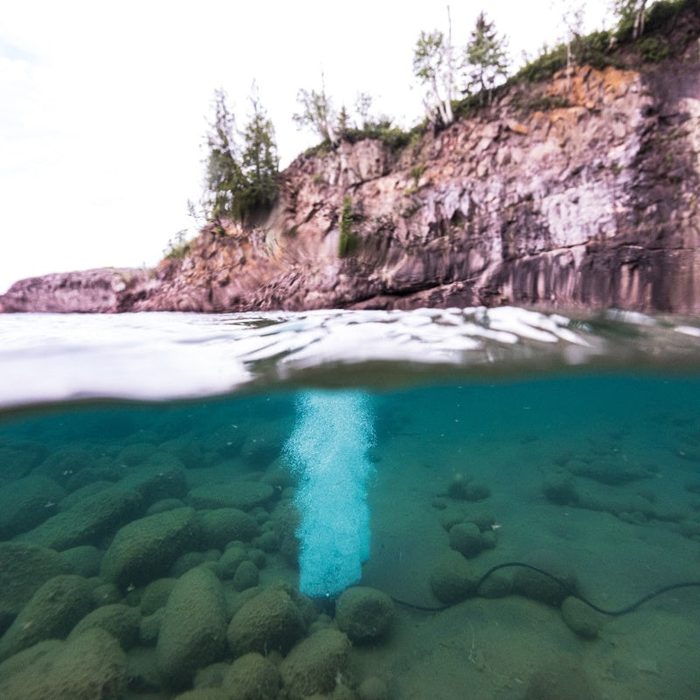 Split waterline view of Kasco Robust Aire diffuser operating beneath lake surface with visible bubble column