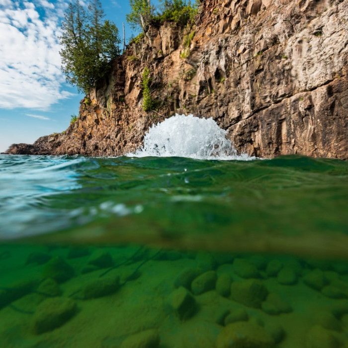 Surface Aerator churning water near rocky cliff shoreline with visible underwater clarity