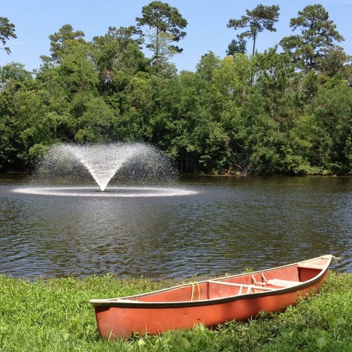 VFX fountain producing a circular spray on a lake with a canoe on the grassy shoreline