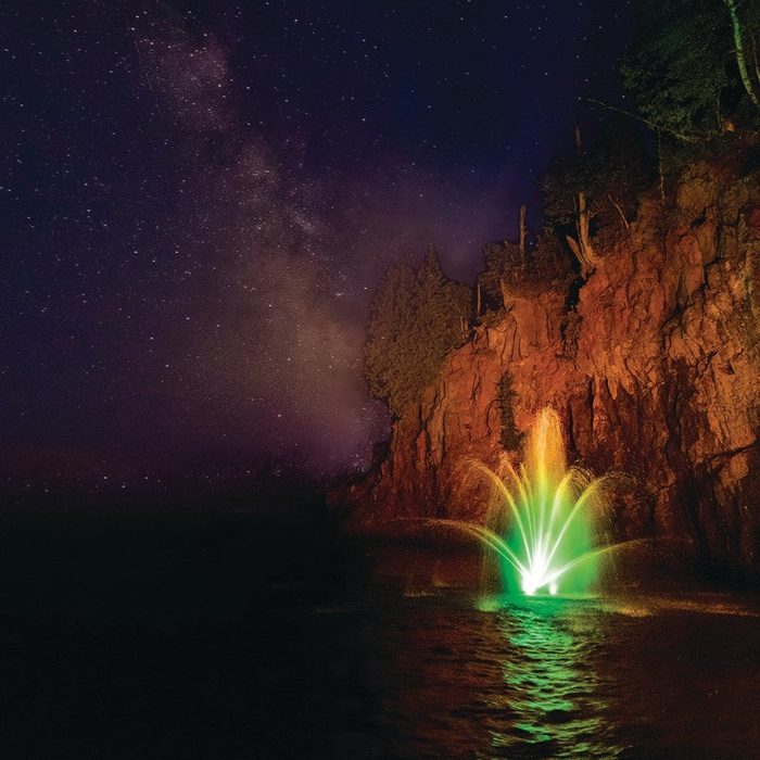 WaterGlow RGB LED Lighting illuminating a decorative pond fountain with multicolor display under a starry night sky